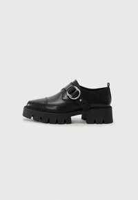 Scarpe in pelle nera con suola spessa e rigata, dotate di un accento in metallo argentato a forma circolare e dettagli di cucitura minimal.