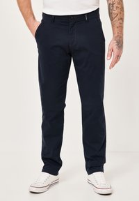 Marineblaue Chinos aus einem glatten Baumwoll-Elasthan-Mix, mit geradem Schnitt, dezentem Nähen und Seitentaschen. Kombiniert mit weißen Sneakers.