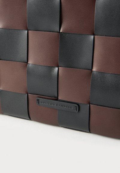 Πλεκτή δερμάτινη τσάντα σε σκούρο καφέ και μαύρο χρώμα. Διαθέτει υφή επιφάνειας και μια μικρή ετικέτα με το λογότυπο της μάρκας ραμμένη στο σχέδιο.