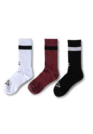 Trois chaussettes à côtes montantes en blanc, bordeaux et noir, chacune avec une bande horizontale contrastante près du haut et un petit texte sur la zone du pied.