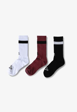 Három bordázott szárú zokni fehér, bordó és fekete színekben, mindegyiken kontrasztos, vízszintes csík a felső résznél, valamint apró szöveg a lábrésznél.