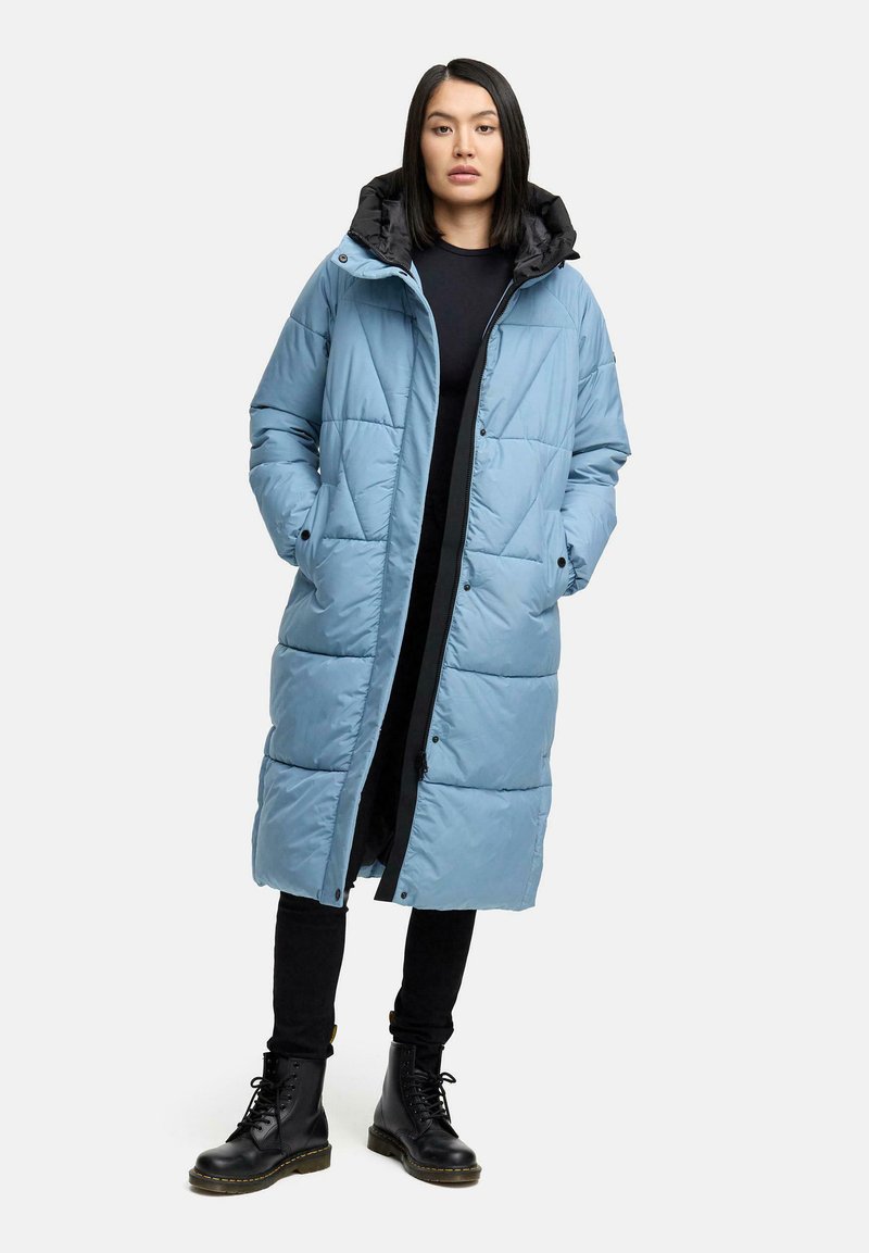 Gaiši zils pildīts mētelis ar melnu kapuci, ar rāvējslēdzēju un pogu aizdari, ar izšuvumu un sānu kabatām.