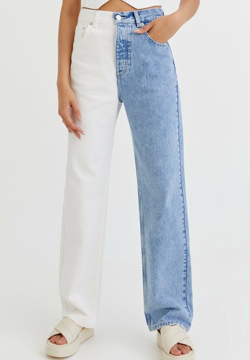 Jean bicolore avec une jambe gauche blanche et une jambe droite en denim bleu clair, avec une coupe droite et une taille haute.