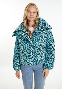 Padded tyrkysová bunda s černými leopard�ími skvrnami, s velkým límcem a knoflíkovým zapínáním, nošená přes bílou košili a světle modré džíny.