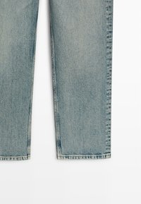 Hellblaue Denim-Jeans mit geradem Bein und sichtbaren Nähten entlang der inneren und äußeren Nähte vor weißem Hintergrund.