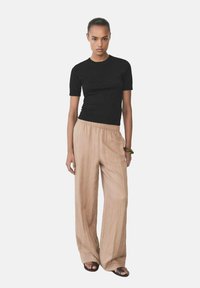 Black fitted t-shirt paired with beige wide-leg trousers. Trousers feature a relaxed fit and elastic waistband, worn with flat sandals.