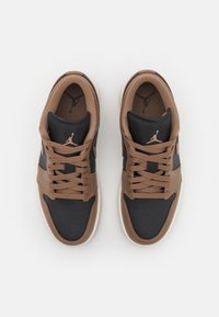 Brązowo-czarne buty sportowe z gładką skórzaną cholewką, perforowanym przodem, płaskimi sznurowadłami i gumową podeszwą z charakterystycznym logo.