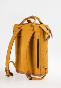 Zaino giallo con design a roll-top, texture in tessuto, spallacci regolabili e imbottiti, e una tasca laterale con zip. Accenti in pelle visibili.