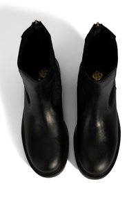 Ein Paar schwarze Lederstiefeletten mit elastischen Seitenpaneelen, von oben auf einem weißen Hintergrund betrachtet.