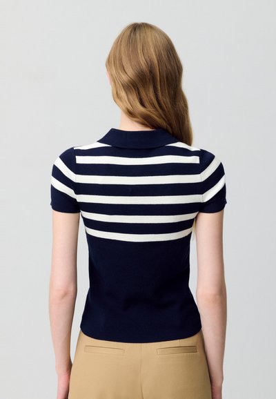 Polo a maniche corte a righe blu scuro e bianche, con colletto, texture a coste e design aderente. La vista posteriore mostra righe orizzontali e tessuto liscio.