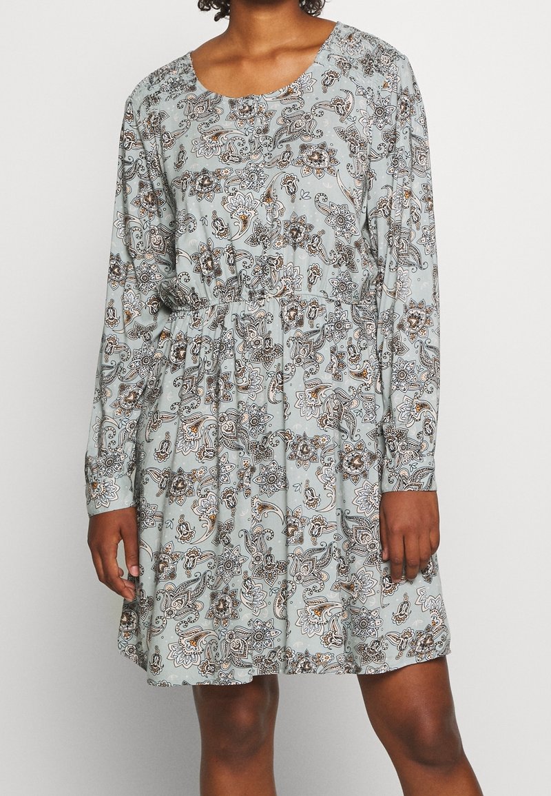 Robe longue à manches longues bleu clair avec un motif cachemire dans des nuances de marron et de blanc, dotée d'une taille élastique et d'un col rond.