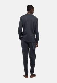 Ensemble composé d'un t-shirt à manches longues gris foncé et d'un pantalon en tissu doux, avec une coupe décontractée et un col rond. Design simple et détails de couture.