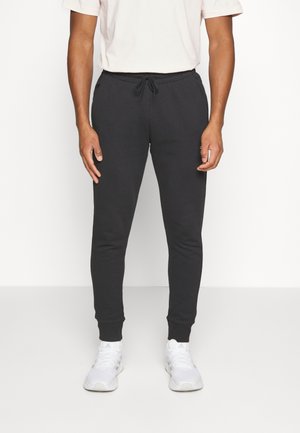 Pantalones de chándal negros con cintura elástica ajustable, piernas ajustadas y puños acanalados, hechos de un tejido suave y texturizado.