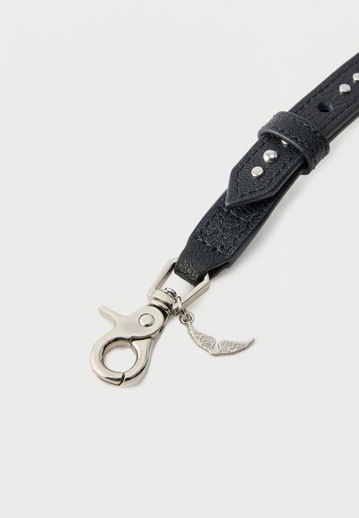 Μαύρο δερμάτινο λουράκι με υφή, ασημένιο μεταλλικό κούμπωμα και μικρό γοργόνα σε σχήμα φτερού κοντά στο κούμπωμα σε λευκό φόντο.