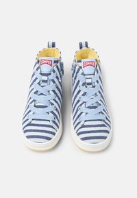 Sneakers in tela a righe blu e bianche con punta rotonda, interno giallo e suole in gomma bianca; presentano un logo rosso "CAMPER" sulla linguetta.