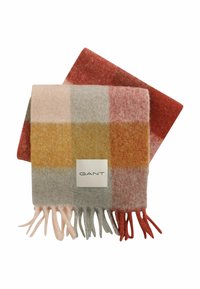 Écharpe en laine douce avec des franges, ornée d'un motif à carreaux dans des teintes de rouge doux, rose, gris et moutarde, étiquetée avec une étiquette "GANT".