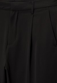 Zwarte broek met een gladde textuur, voorzien van voorplooien en zijzakken. De tailleband is plat met een subtiele gestikte afwerking.