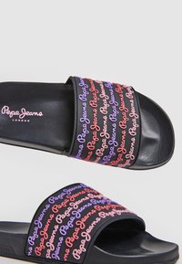 Juodi slydimo sandalai turi ryškiai spalvotą "Pepe Jeans" prekės ženklą violetinės, rožinės ir raudonos spalvų ant juostos. Lygus paviršius su tekstūruotu padu.