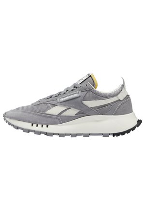 Baskets Reebok basses gris et blanc avec panneaux en suède et mesh, semelle blanche rembourrée, et détails de marque sur le côté et la languette.