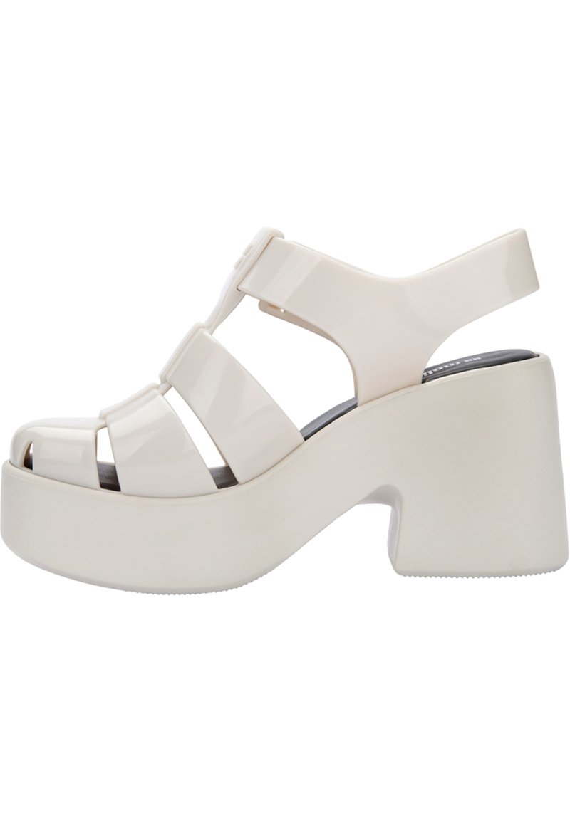 Sandali piattaforma bianchi con una finitura lucida, caratterizzati da cinturini larghi, punta aperta e un tacco alto. Suola piatta per maggiore stabilità.