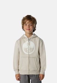 Sudadera con cremallera de color beige claro en tejido suave, que presenta un gran logo blanco, dos bolsillos frontales y puños y dobladillo de canalé.