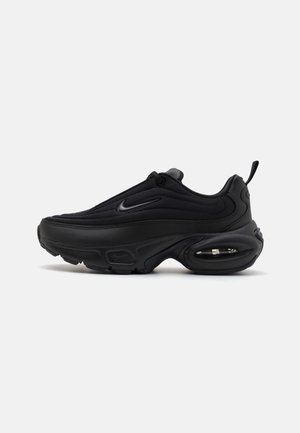 Black athletic shoe with a smooth, textured upper. Features a round toe, padded collar, and visible air cushioning in the sole.