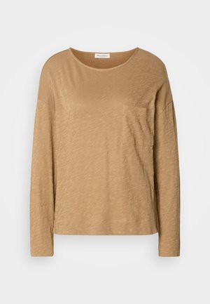 Ilga rankovė, šviesiai ruda palaidinė, pagaminta iš minkšto, tekstūruoto audinio. Turi apvalų iškirpimą ir vieną krūtinės kišenę. Pravažiuojantis kirpimas.