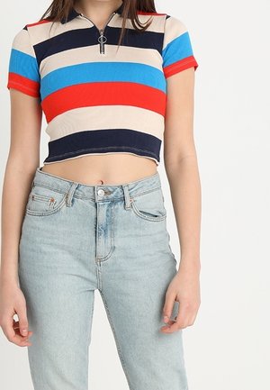 Prążkowany krótki top z krótkim rękawem i zamkiem przy kołnierzu w niebieskie, czerwone, granatowe i beżowe paski, w zestawie z wysokim stanem jasnoniebieskich dżinsów.