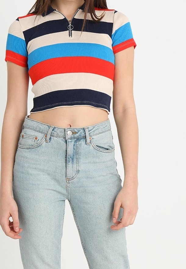 Top court à manches courtes à rayures bleu, rouge, marine et beige, à col zippé, associé à un jean taille haute en denim clair.