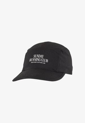 Gorra negra con visera plana, con texto blanco: "CLUB DE CORRER DEL DOMINGO" y "OTRO LABORATORIO DE ALGODÓN". Hecha de material de algodón ligero.