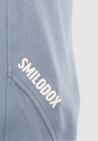 Modrý mikinový svetr s texturovaným povrchem, bočními švy a výrazným bílým logem "SMILODOX".