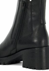 Black leather ankle boot with a chunky heel, side zipper, textured rubber sole, and smooth finish. Features minimal stitching details.