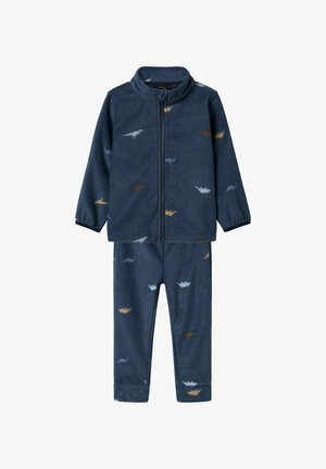 Tumši zila flīsa pidžamu komplekts ar rāvējslēdzēja jaku un biksēm, ar maziem dinozauru rakstiem bēšā un gaiši zilā krāsā. Mīksta tekstūra.
