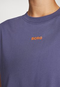 Purple cotton T-shirt featuring a crew neck and a small orange "BORG" logo on the upper chest area. Smooth texture and relaxed fit.