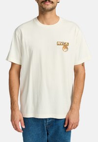 Cream cotton t-shirt with short sleeves, a crew neck, and a brown graphic design featuring "RVCA" and a circular pattern on the chest.