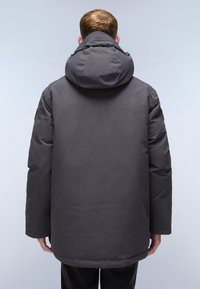Grå isolerad parkas med en stor huva, slät yta och sydda detaljer. Har en något längre baksida och minimalistisk design.