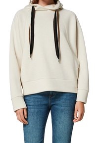 Kremowa bluza z kapturem wykonana z miękkiego materiału, z kieszenią kangurką, wyposażona w czarne i brązowe sznurki. Luźny krój z ściągaczami przy mankietach i u dołu.