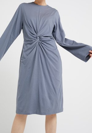 Midikleid in Schieferblau mit langen, weiten Ärmeln und einem verdrehten Knotendetail an der Taille vor hellem Hintergrund.