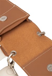 Brun læderpung med metaltrykknaplukning, indvendig suede-textur, beige stofrem og synlige sølvhardware-detaljer.