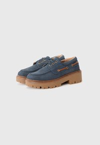 Blaue Wildlederschuhe mit einer dicken braunen Gummisohle, mit goldenen Ösen, braunen Akzenten und einem runden Zehendesign.