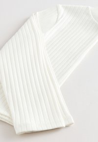 Tela blanca acanalada con una textura suave, que presenta un diseño ajustado y una forma estructurada. El material parece elástico y ligero.