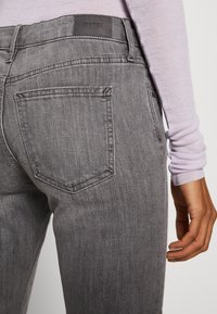 Gray denim jeans with a five-pocket design, featuring a back pocket, and an Esprit logo on the waistband. The material has a subtle texture.