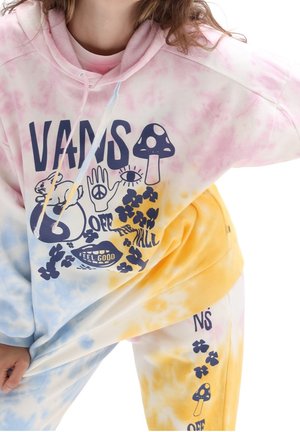 Personne portant un sweat à capuche et un pantalon tie-dye rose, bleu et jaune avec des logos Vans, un champignon, des fleurs, un signe de paix et le texte "Feel Good".