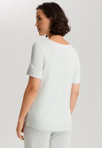 Top azul claro de manga corta con escote redondeado y textura sutil. Presenta mangas enrolladas y un corte relajado, fabricado en tejido suave.