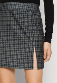 Grå rutig mini kjol med mörkblå ränder, med en sidodel och slät textur. Tillverkad av lätt tyg, lämplig för vardagsbruk.