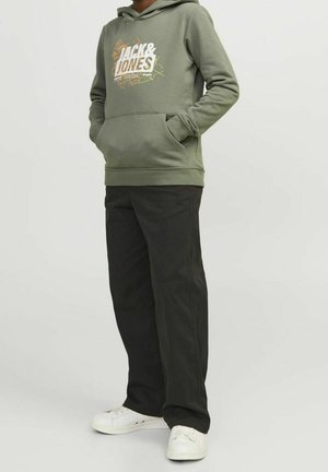 Sweat à capuche vert olive avec un logo blanc et un motif graphique ; assorti à un pantalon noir et des baskets blanches. Tissu doux, coupe décontractée.