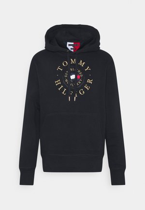 Sweat à capuche noir Tommy Hilfiger avec texte de logo doré et emblème circulaire aux couleurs blanc, bleu et rouge du drapeau sur le devant, avec capuche et poche avant.