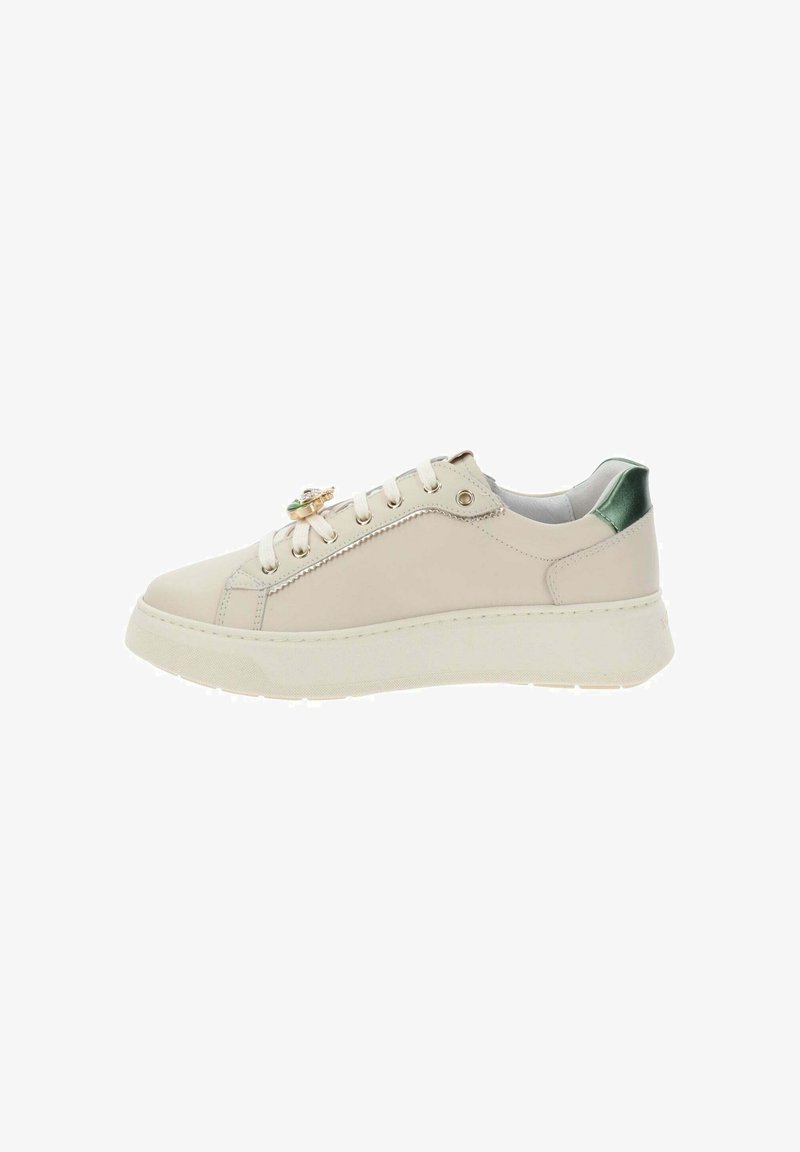 Crème lage sneakers met witte veters, dikke zool, groene hieltab en gouden decoratieve hanger aan de zijkant.
