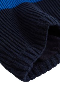 Mörkblå stickad tröja med ribbat mönster och kontrasterande blå rand. Har en rund halsringning och mjukt, tjockt material.