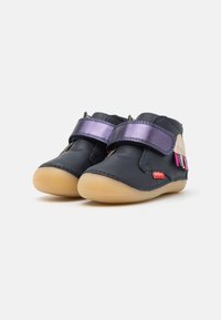 Bottes chelsea en cuir bleu marine avec une sangle violette, une semelle beige et des détails colorés. Bout arrondi et texture douce adaptées aux enfants.